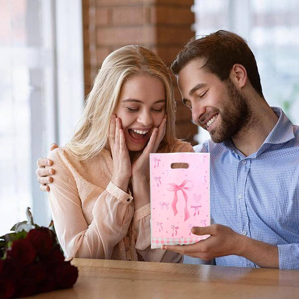 Pink bow gift bag with cutout handle held by people