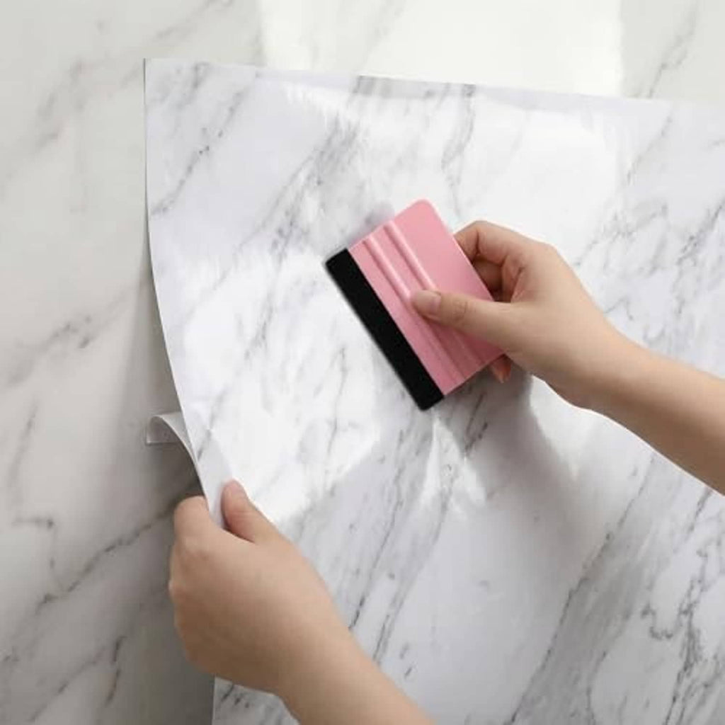Vinyl wrap squeegee with felt edge, pink scraper held by hands on flat film