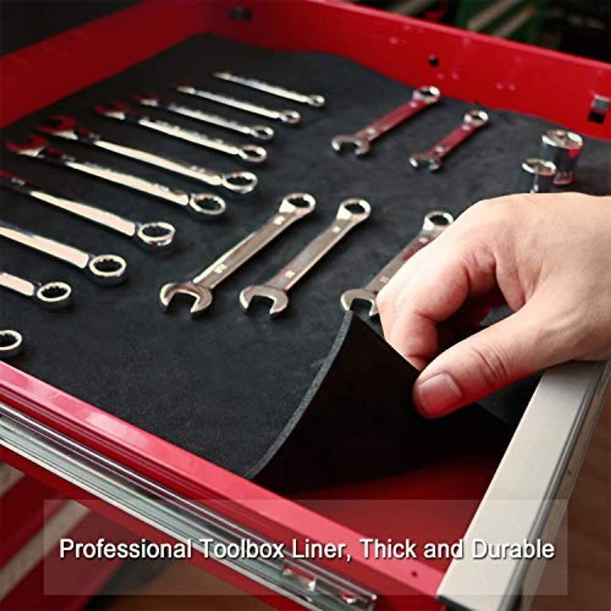 Black tool box liner with wrenches and hand placing a tool, thick durable mat