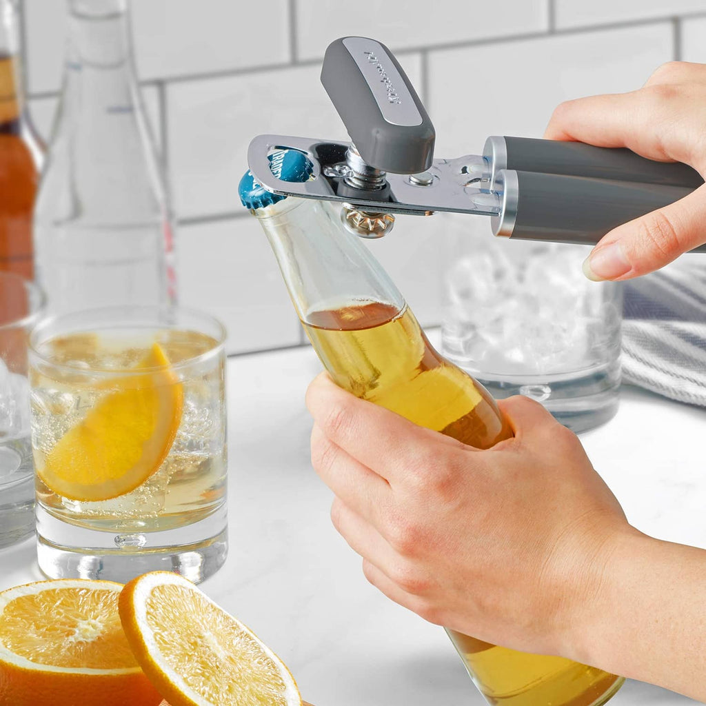 KitchenAid bottle opener with charcoal handles lifting a bottle cap on glass bottle