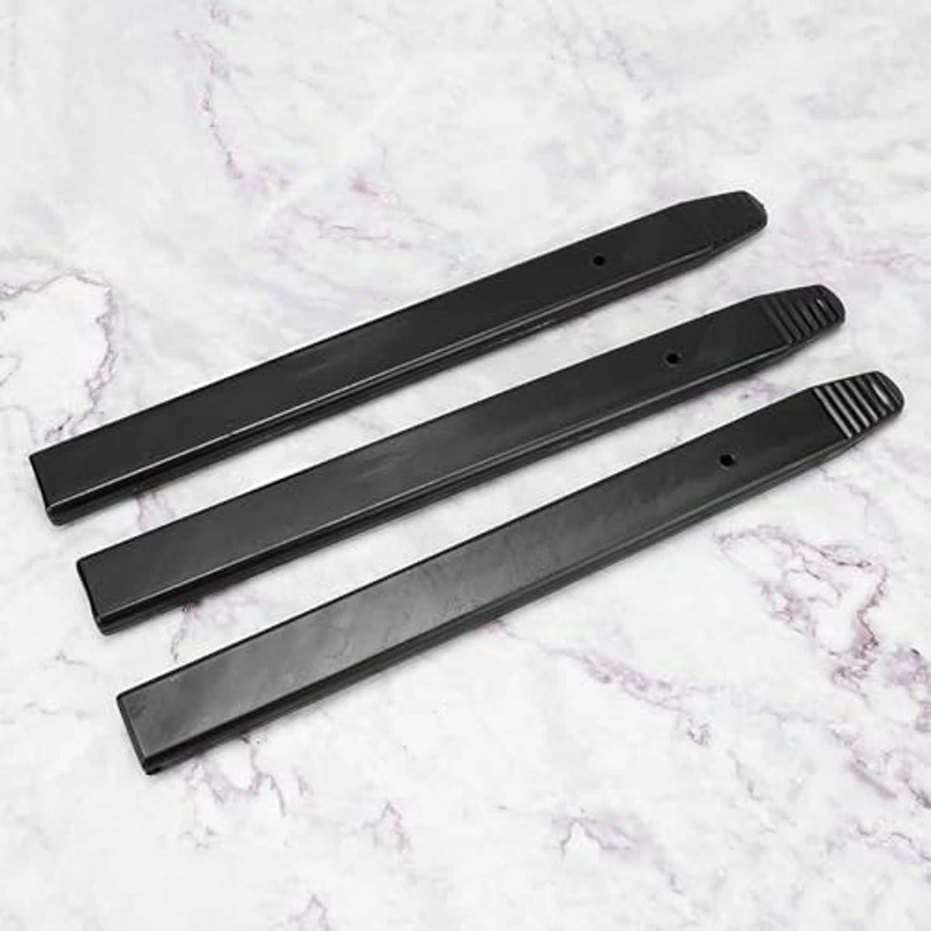 Three long black tire pry bar protector sleeves on light marble surface