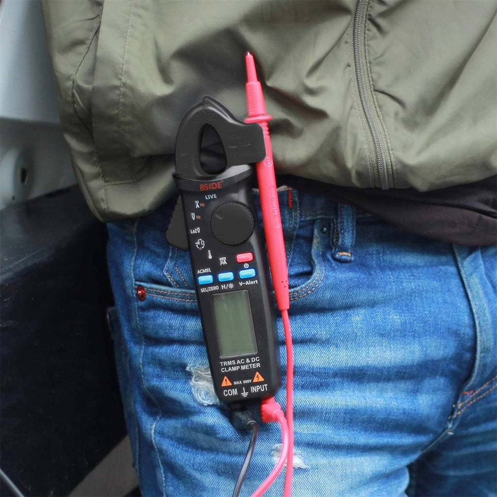 Digital clamp meter on clothing with red and black leads connected and LCD readout visible