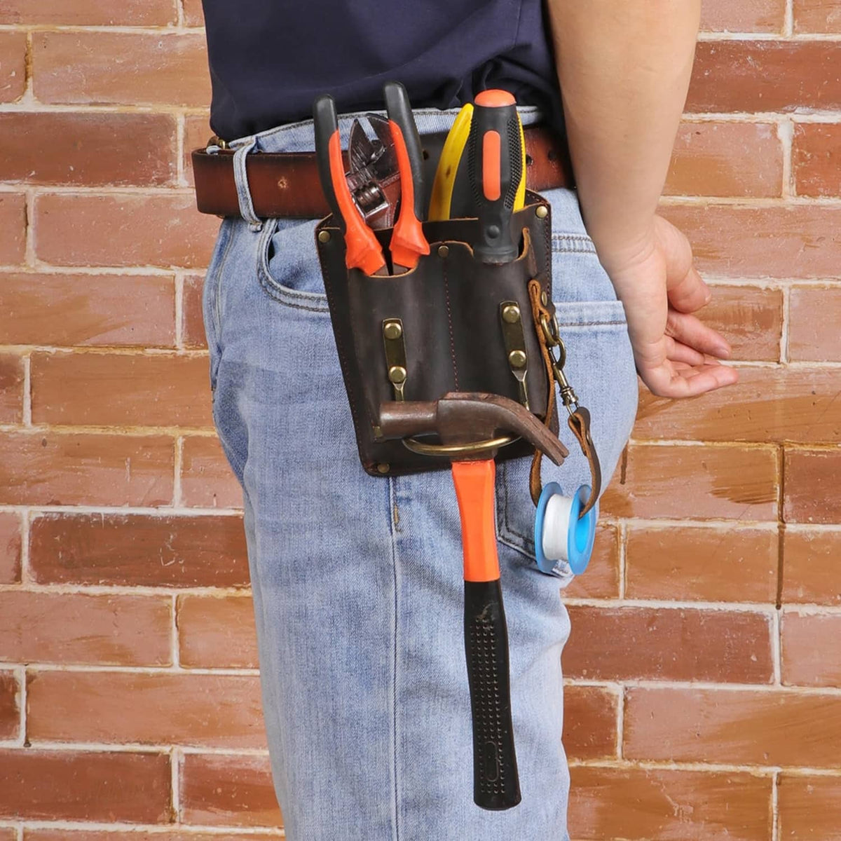 Brown leather tool holster worn on belt with open pockets holding tools and tape
