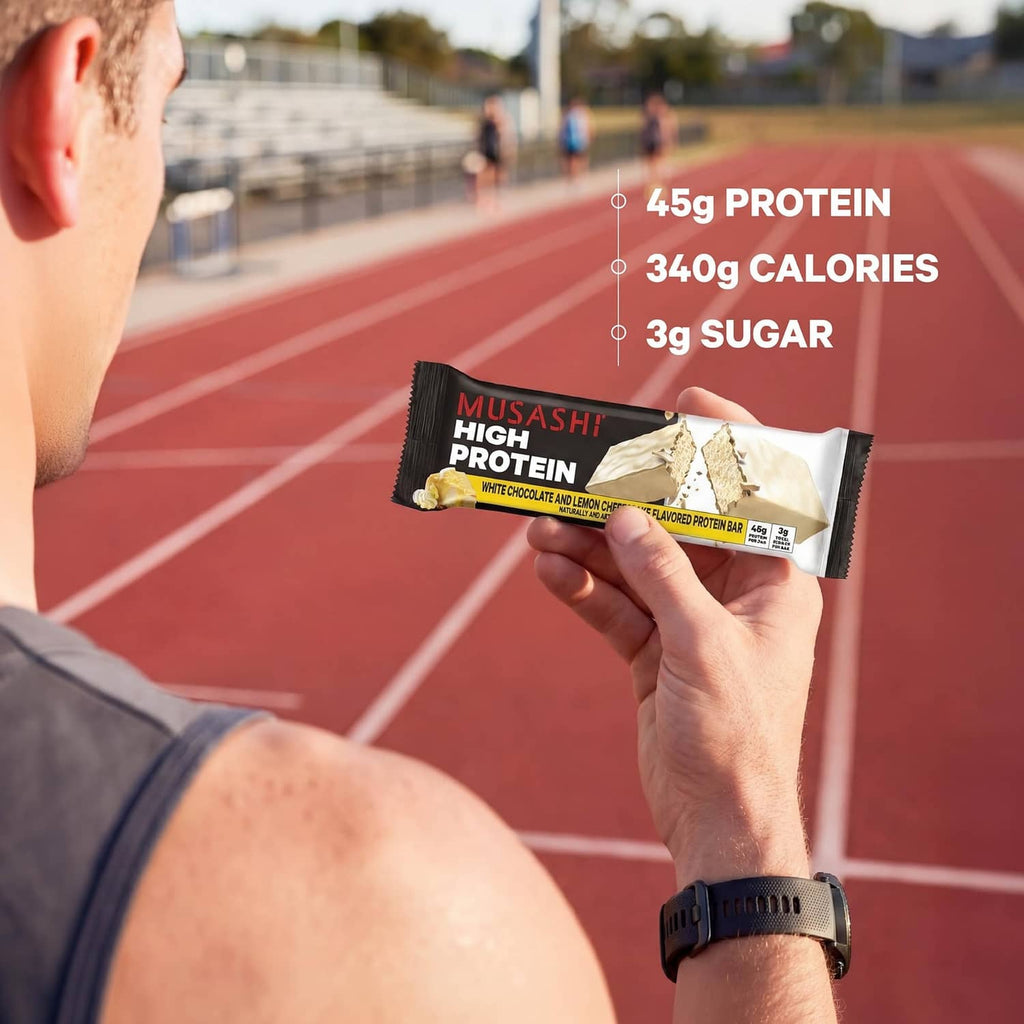 White chocolate and lemon cheesecake protein bar held in hand, black wrapper