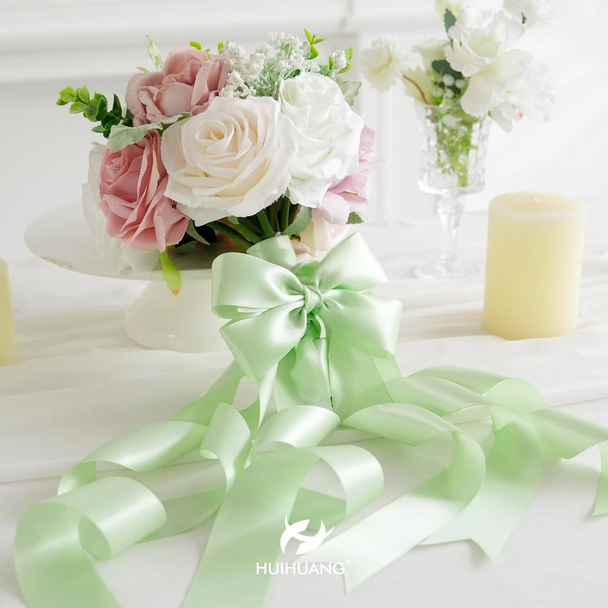 Seafoam green satin ribbon bow with flowing ribbon loops across a floral arrangement.