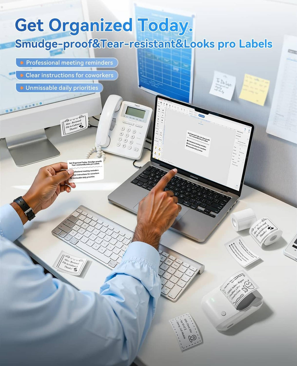 Grey label printer on a desk with labels, keyboard, and phone for organization