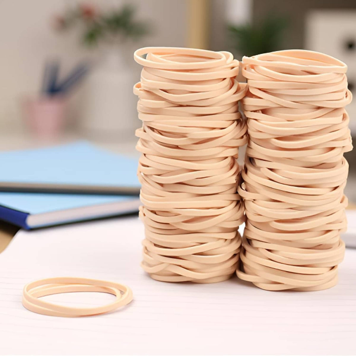 Beige elastic rubber bands in two tall stacks with one ring lying on top