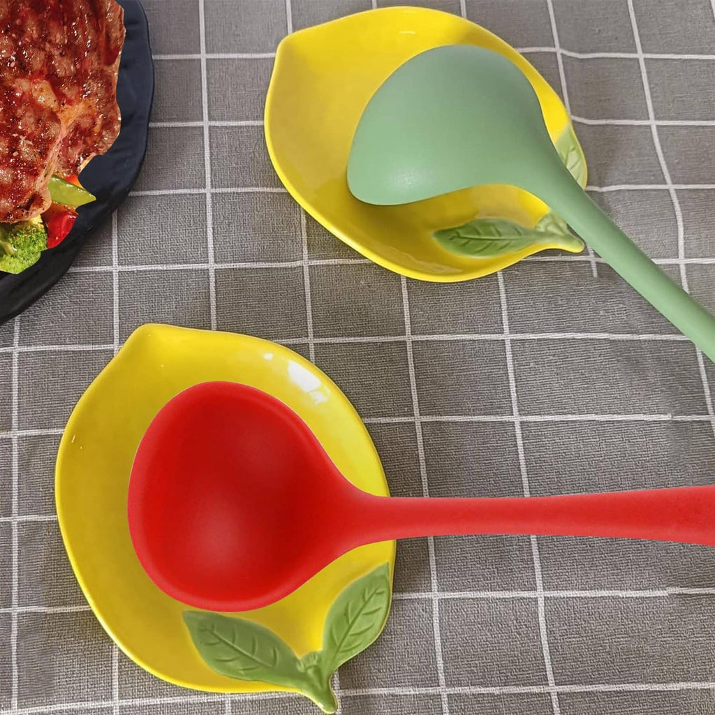 Yellow ceramic lemon-shaped spoon rest with green leaf sides and light green spoon