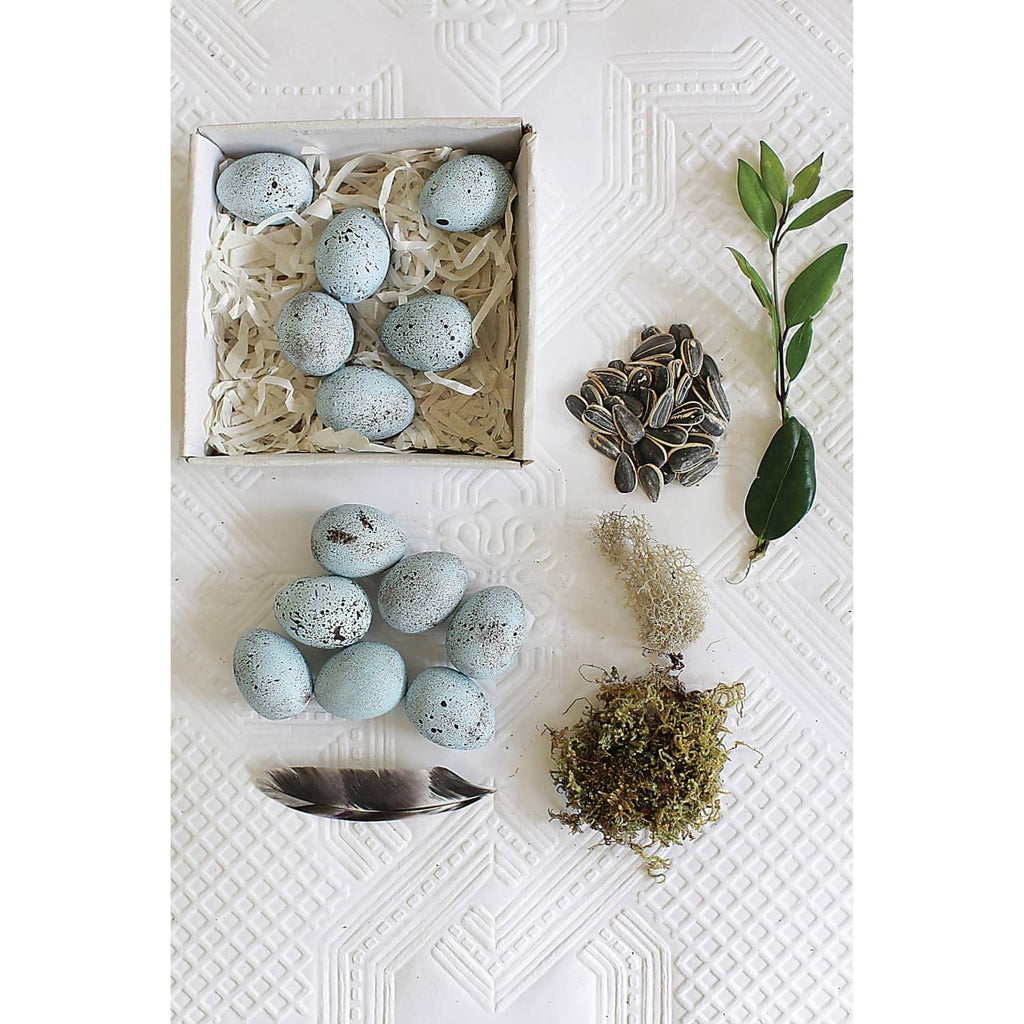 Blue speckled ceramic eggs with decorative feather, pine cone, and dried greenery