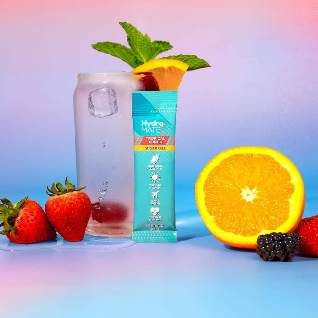 HydroMate Tropical Punch sugar-free hydration packet, beside glass and fruit