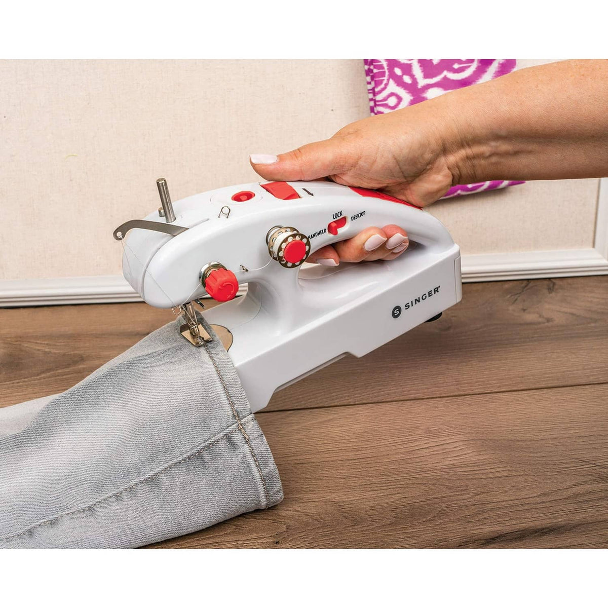 Handheld cordless mending machine stitching a denim pant leg