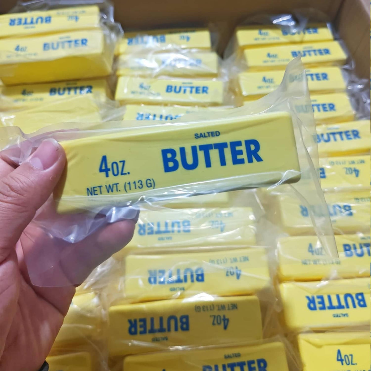Hand holding a yellow salted butter squishy fidget toy from a stacked set