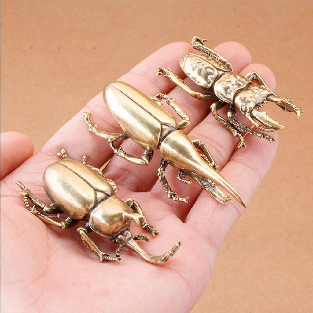 Set of miniature brass beetle ornaments shown on an open palm