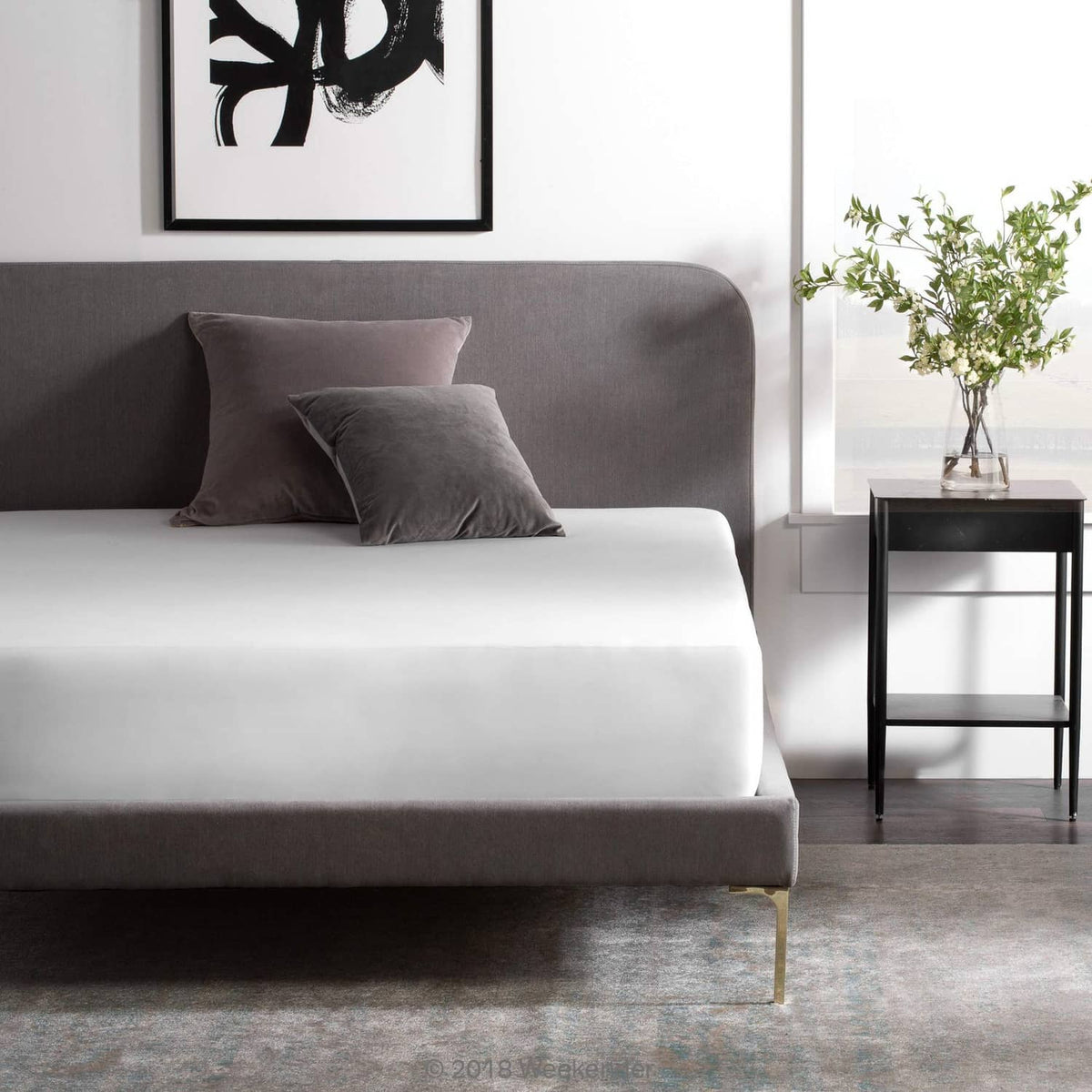 Fitted jersey mattress protector on bed, white top with dark gray edge