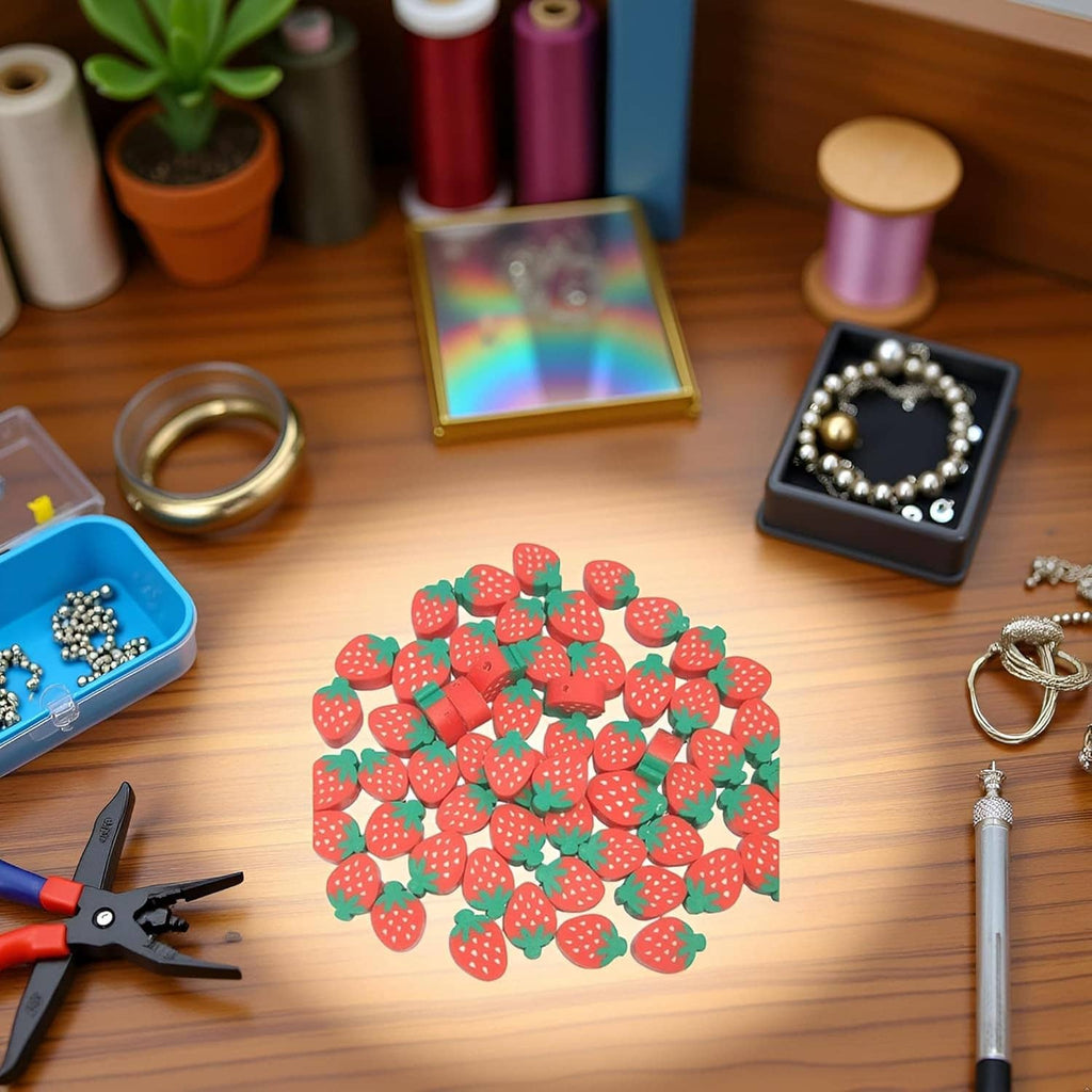 Strawberry-shaped polymer clay beads laid in a cluster on a tabletop.