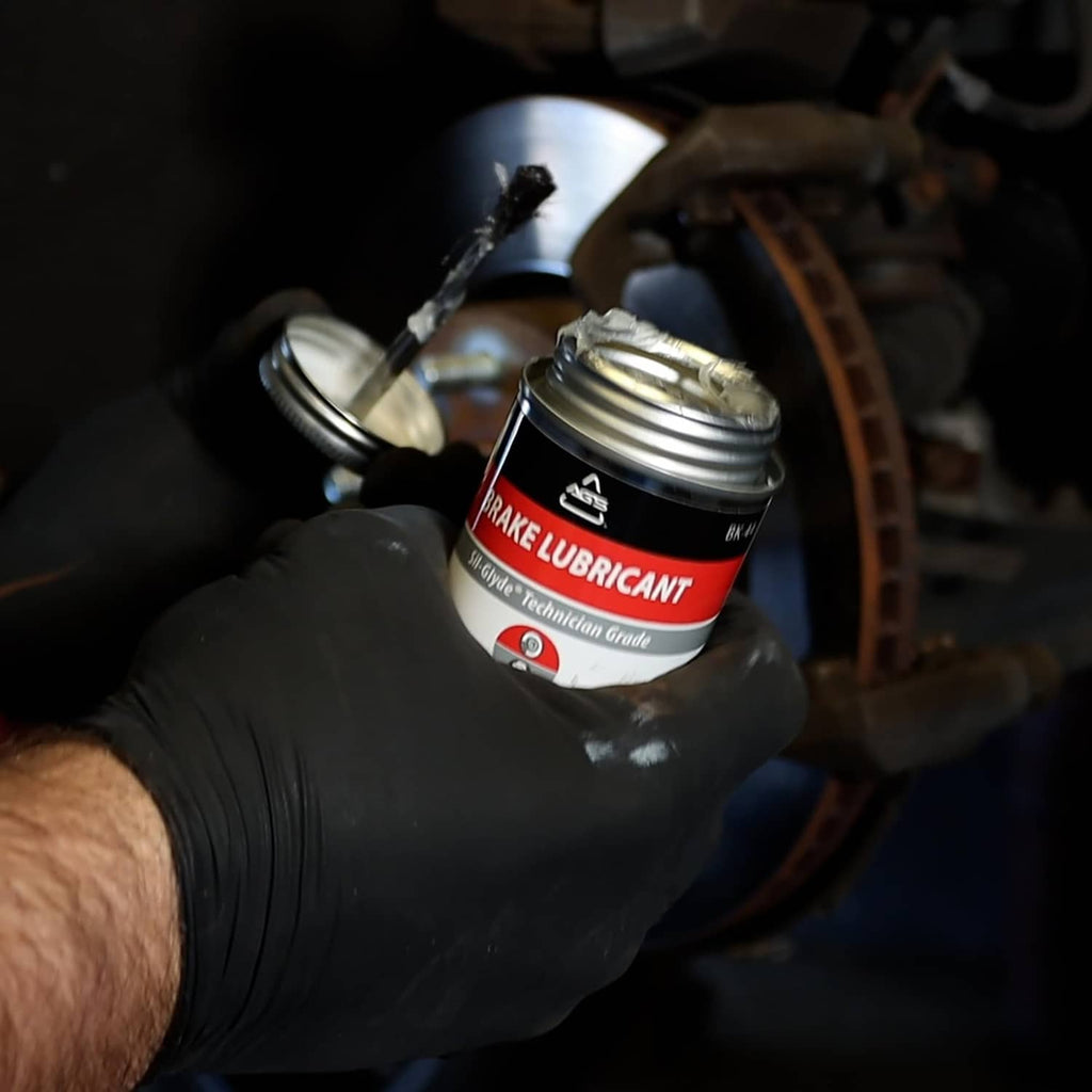 Gloved hand holds AGS SIL-Glyde silicone brake grease and brush applicator