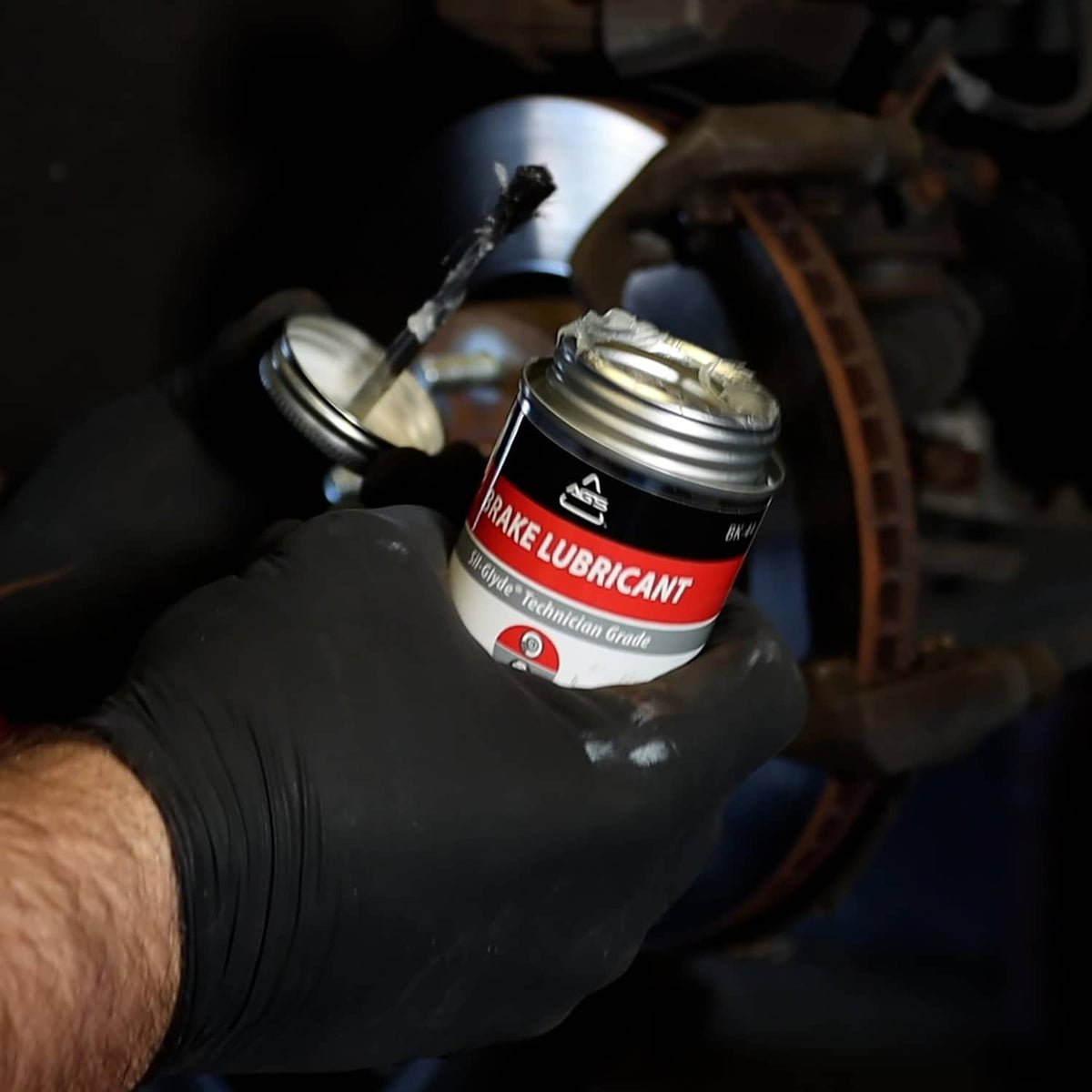 Gloved hand holds AGS SIL-Glyde silicone brake grease and brush applicator