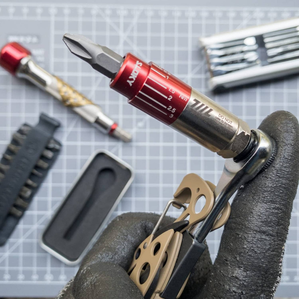 Red mini torque driver with hex bit tip held in a gloved hand