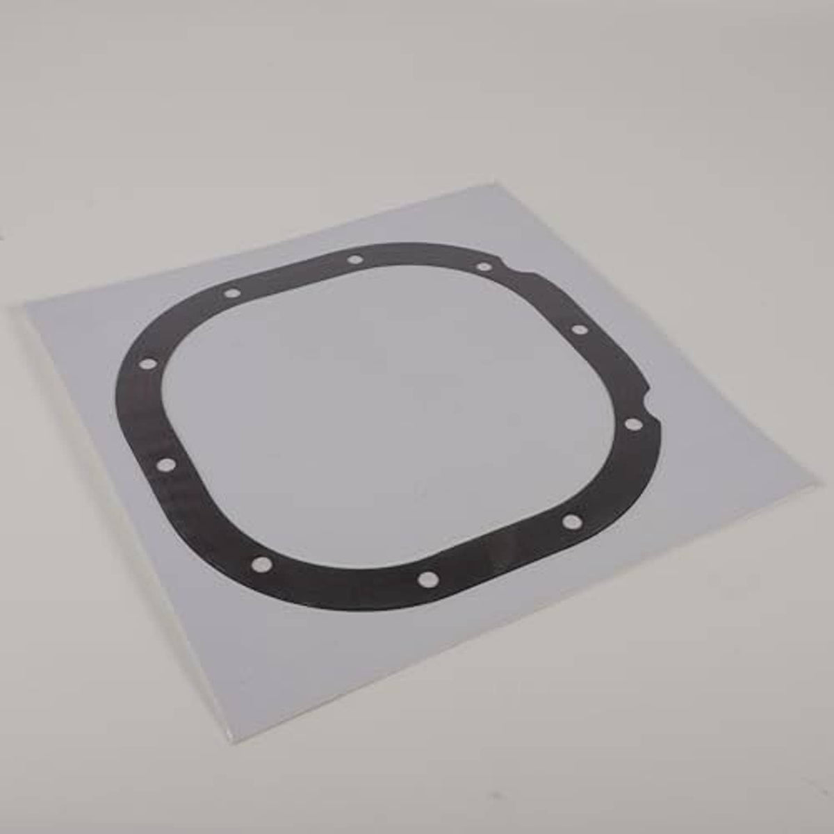 Rear differential cover gasket lying on a card, dark ring with bolt holes