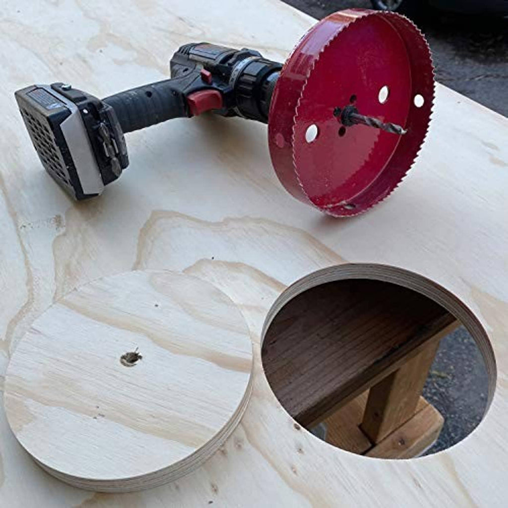 Red bi-metal hole saw drilling a circular hole in a light wood board.