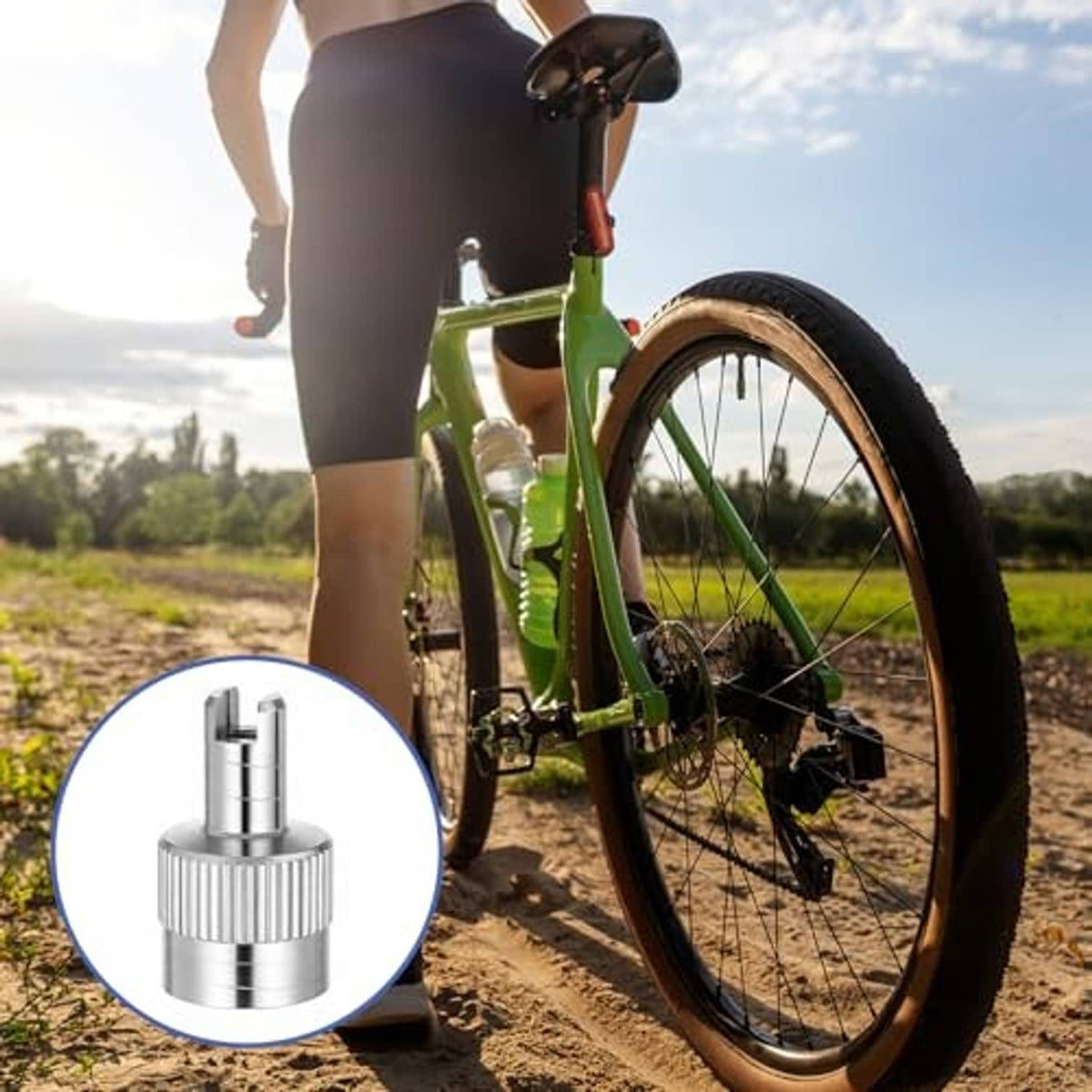 Silver slotted tire valve stem cap with valve core shown with a bicycle wheel