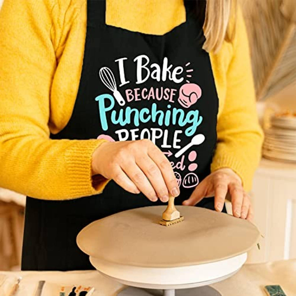 Black baking apron with 'I Bake' slogan worn while stamping dough