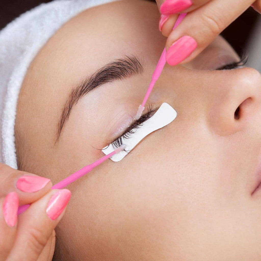 Pink micro swab applying product along an eyelash line on a client