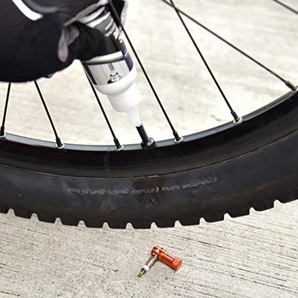 Red Presta valve cap on a bicycle tire near the rim and spokes