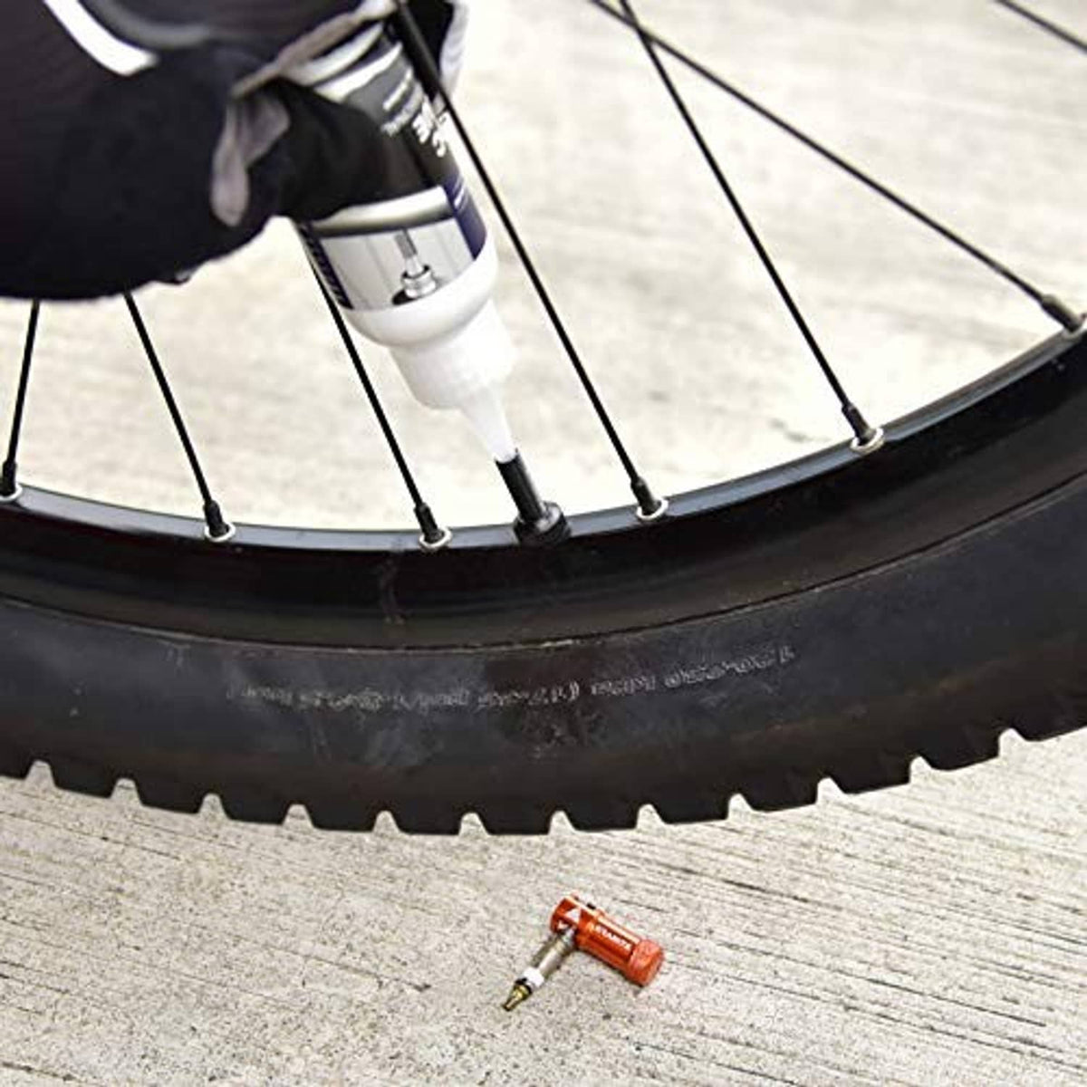 Red Presta valve cap on a bicycle tire near the rim and spokes