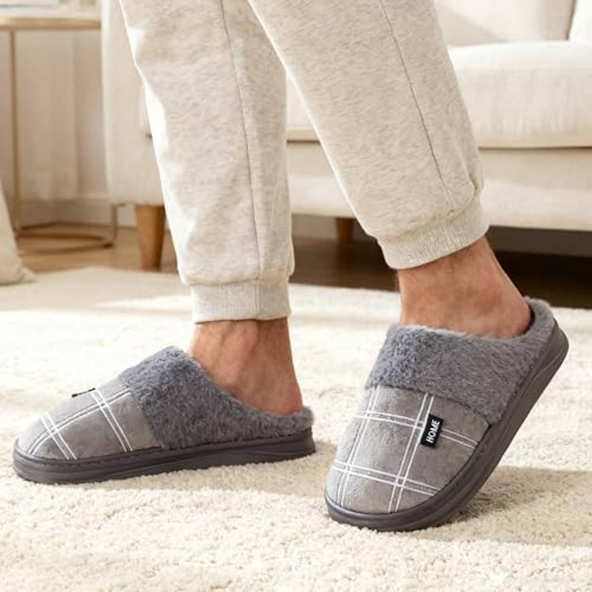 Grey plush house slippers on feet with jogger pants, slip-on slide style