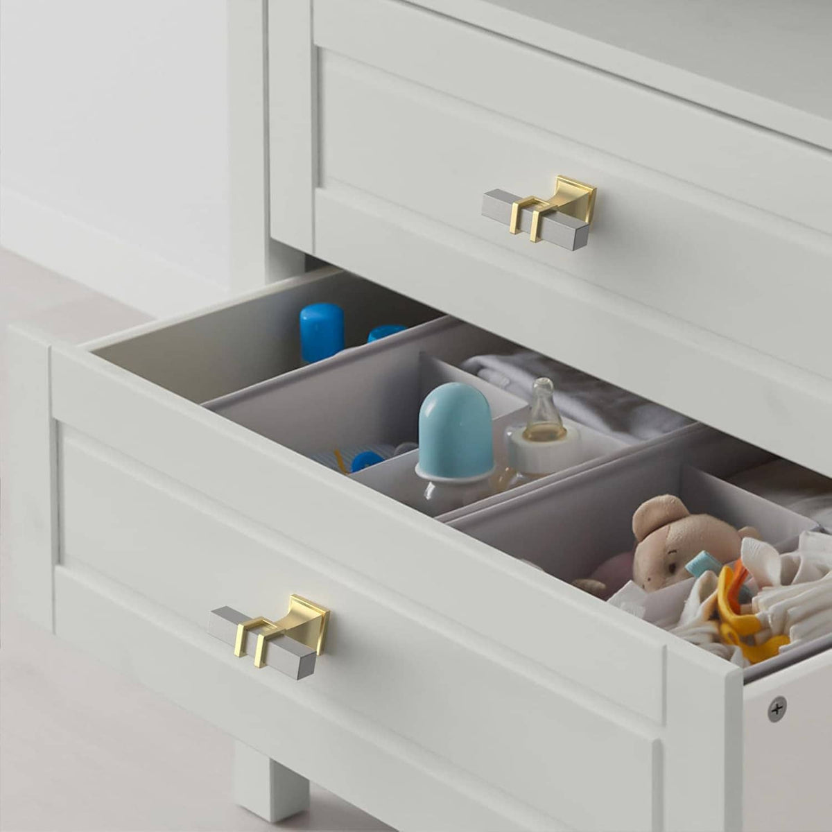 Two-tone gold and brushed satin nickel drawer knob, shown on open cabinet drawer