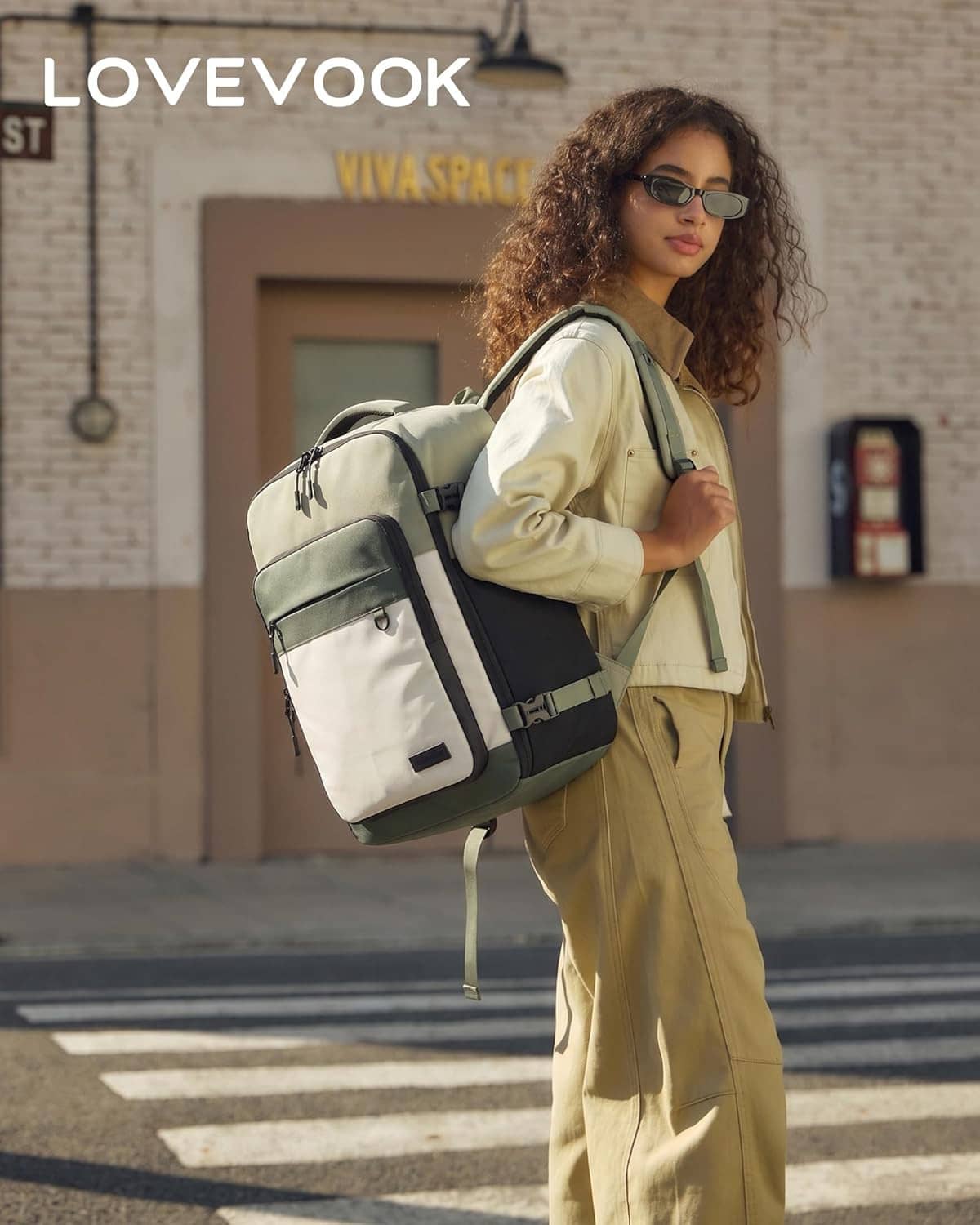 Olive and cream travel backpack worn outdoors with front zip pocket and shoulder straps