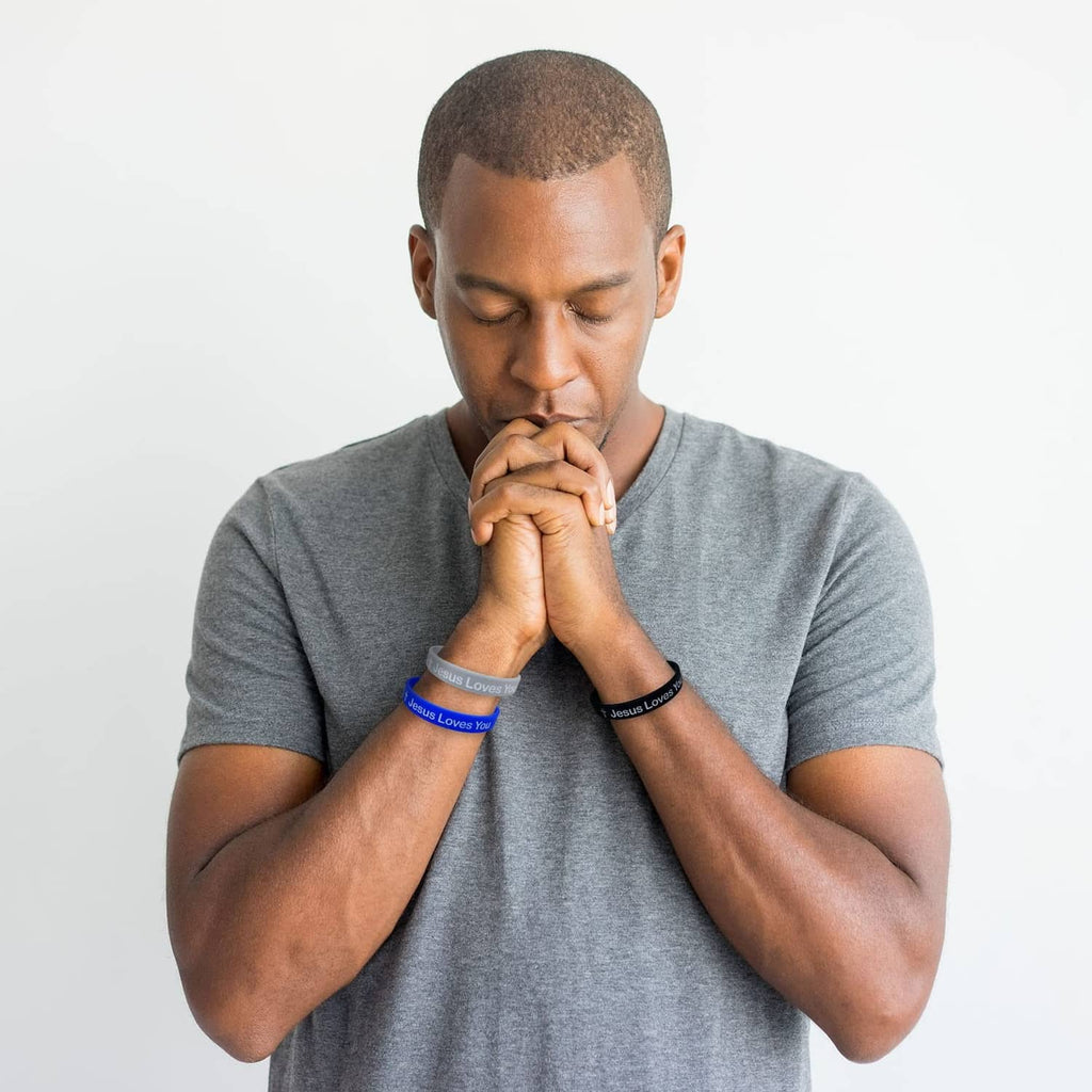 Dark blue silicone wristband with “Jesus Loves You” on a man’s wrist