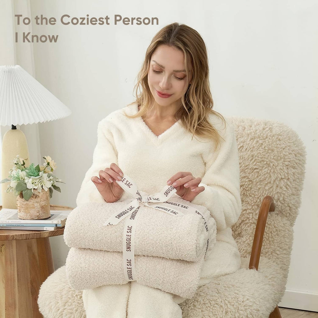 Ivory plush throw blanket folded and held by person, fuzzy sherpa texture