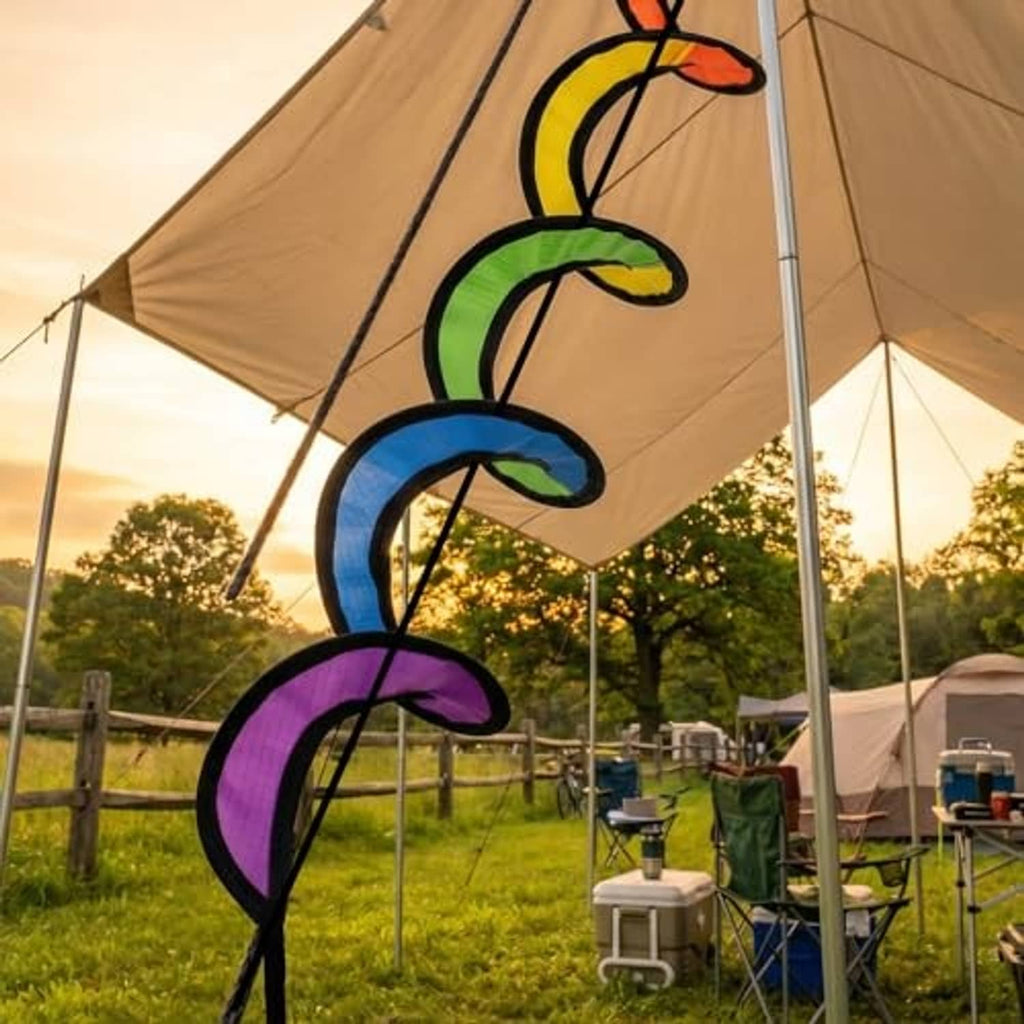 Rainbow wind spinner swirls hanging from a tent pole at outdoor gatherings