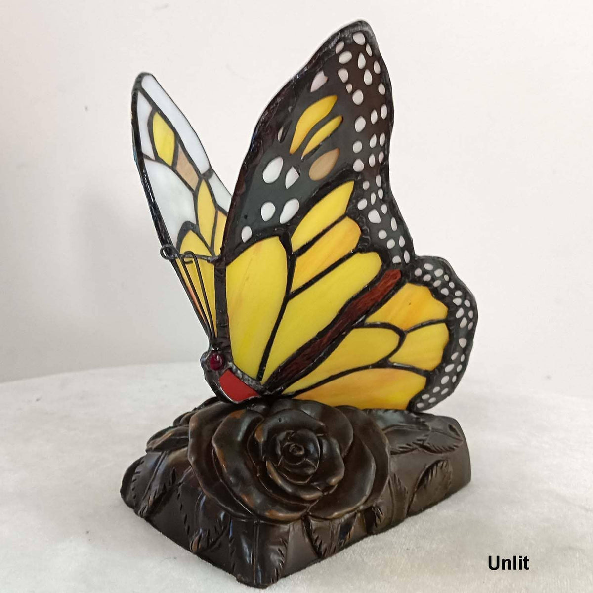 Unlit monarch butterfly accent table lamp with yellow stained-glass wings on dark base