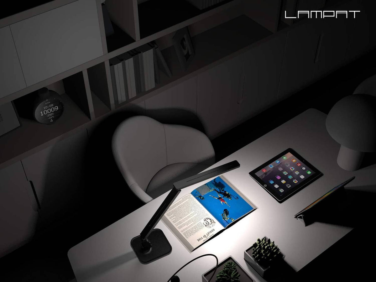 Black LED desk lamp casting light on a tablet and open book