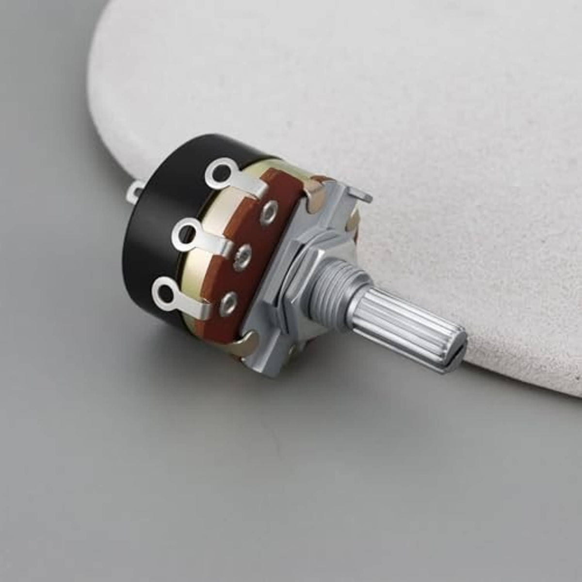 Side view rotary potentiometer with mounting holes, red-brown contact strip, metal shaft