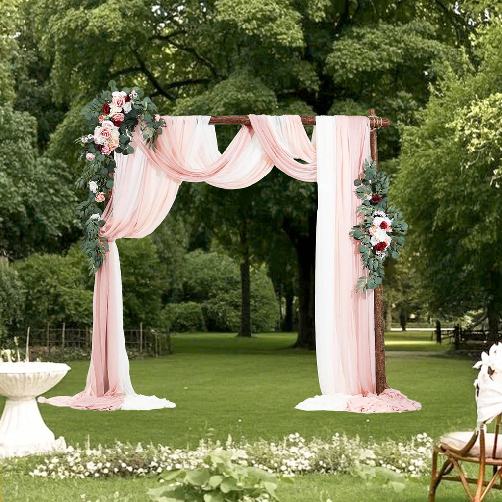 Pink wedding arch with sheer drapes and artificial mixed flower garlands on two posts