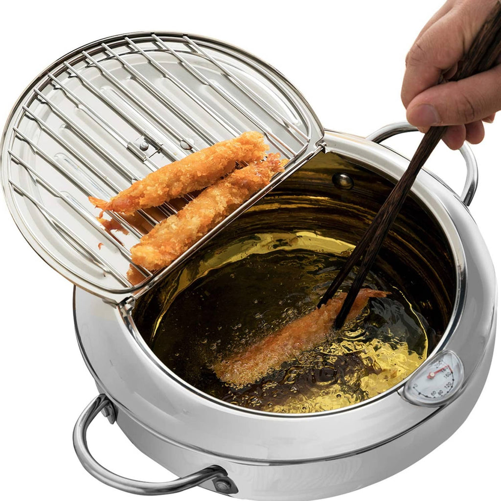 Stainless steel deep-fryer pot with wire basket and handles, holding fried chicken in hot oil