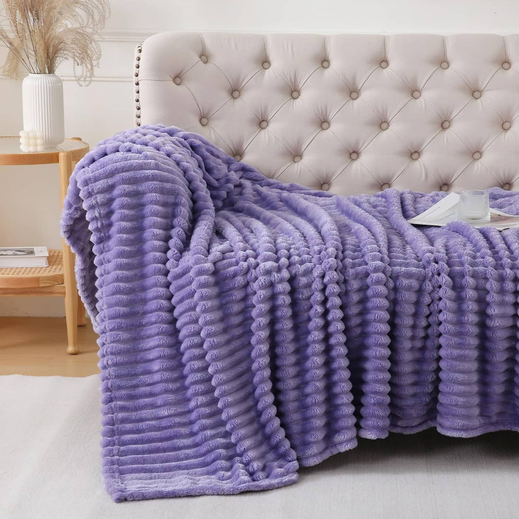 Lavender plush throw blanket folded and draped on tufted sofa back