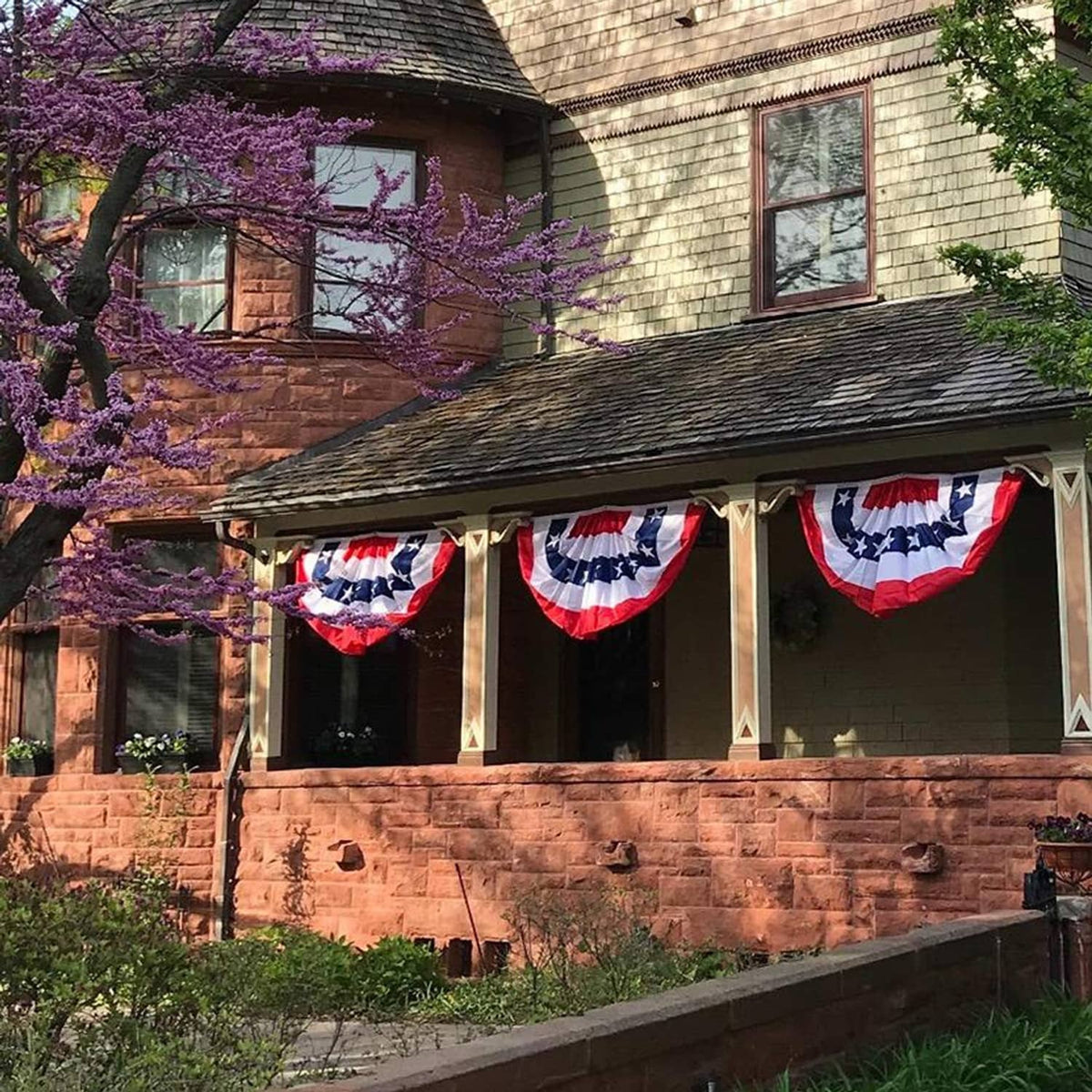 Patriotic pleated fan bunting flags hanging across a yard display, red white blue stars