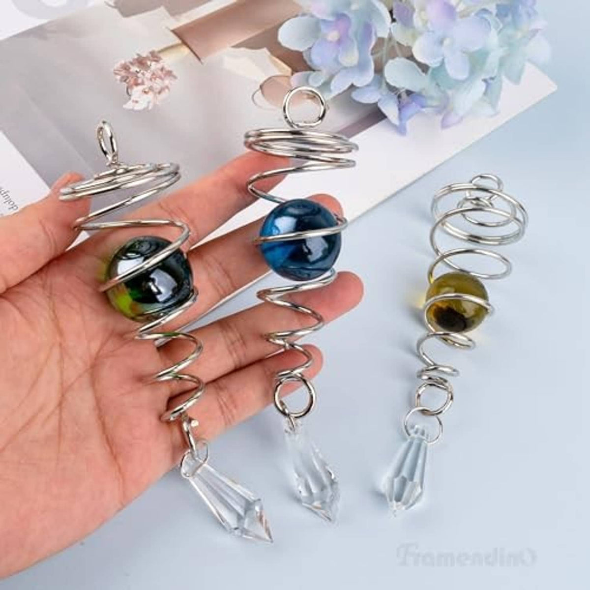Hand holding three gazing ball wind spinners with colored glass balls and crystal drops