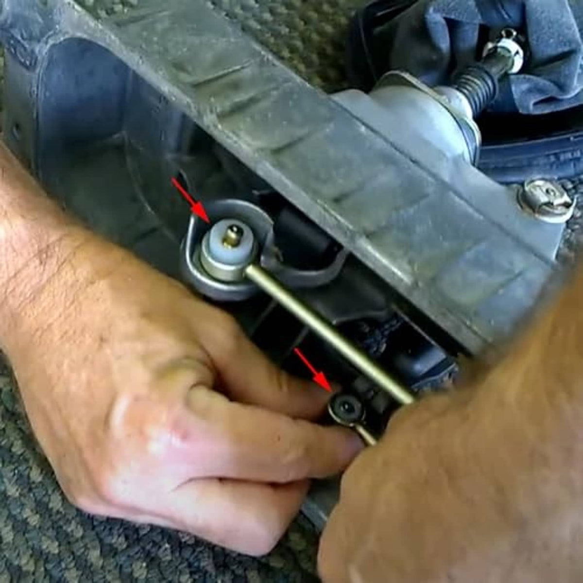Hands installing a shift cable bushing replacement on the vehicle linkage