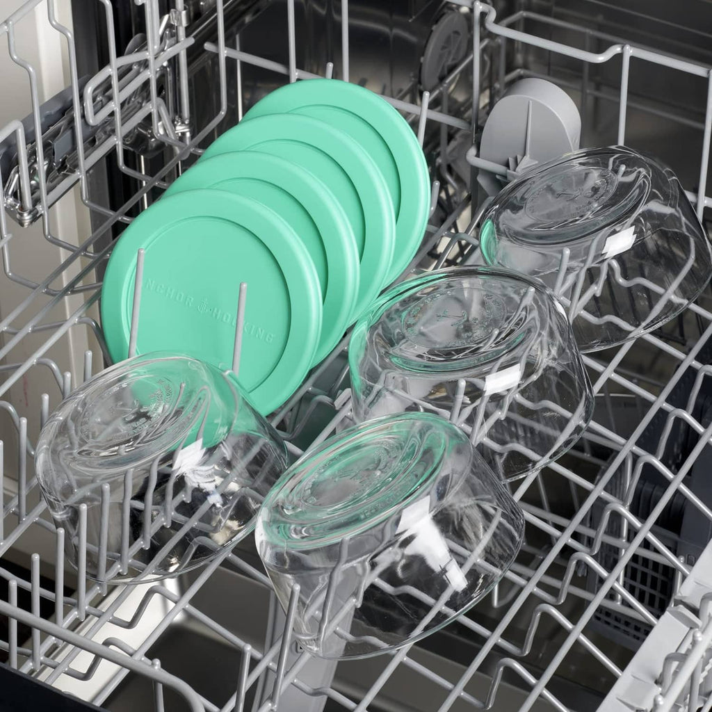 Glass food storage containers with teal lids in a dishwasher rack