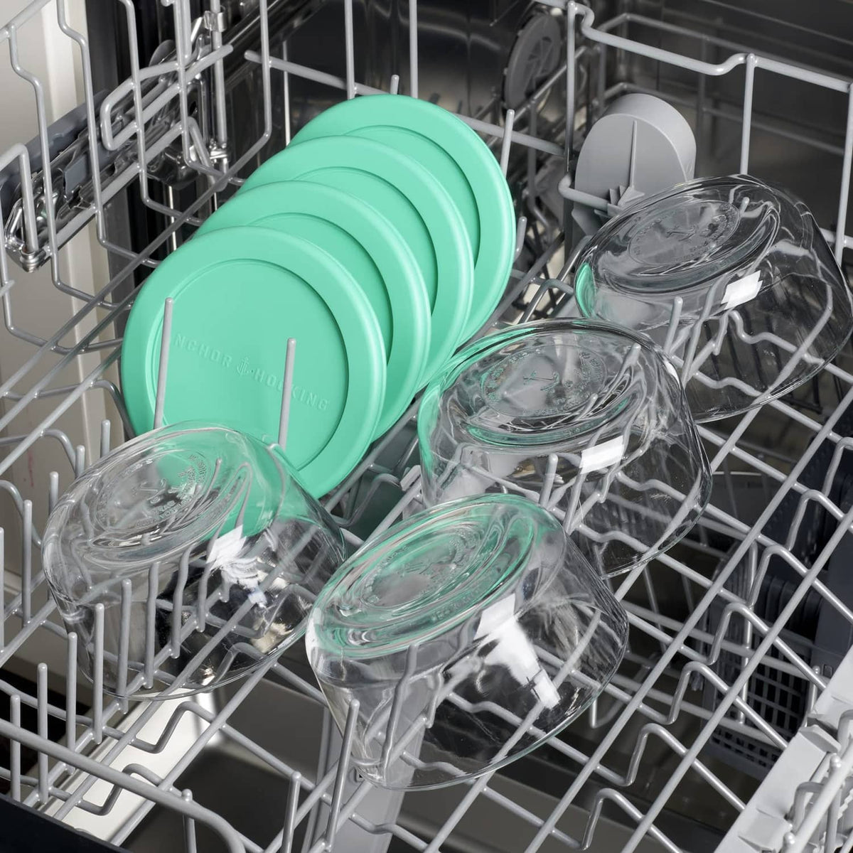 Glass food storage containers with teal lids in a dishwasher rack