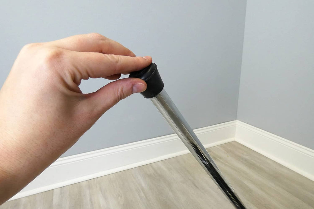 Hand installs black rubber chair leg tip onto a metal chair leg