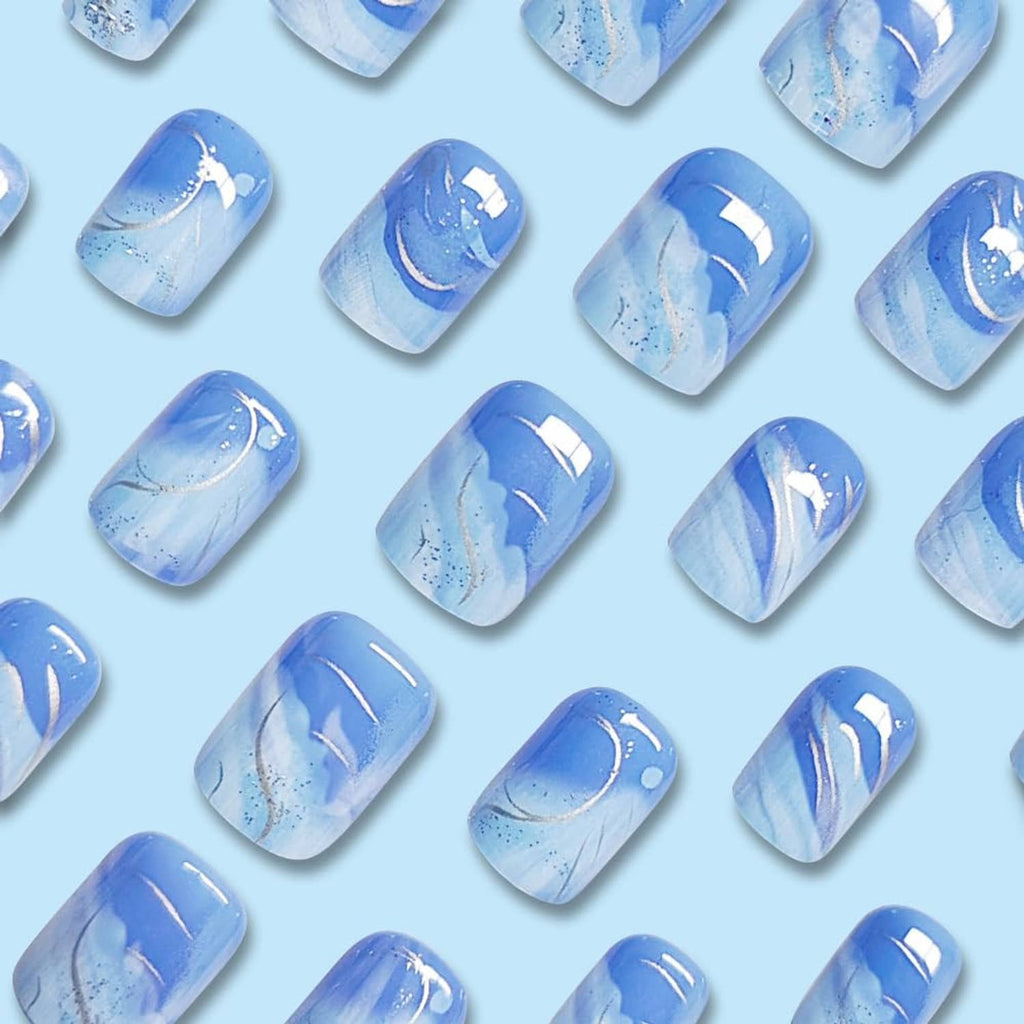 Short square press-on nails with blue gradient and white swoosh lines, sparkly finish
