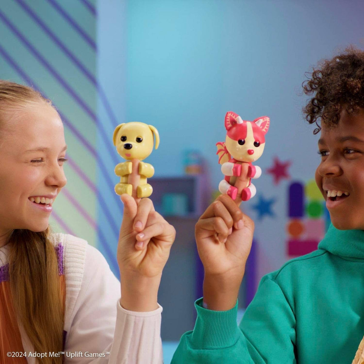 Two kids holding small cat and dog collectible figures on pink and blue background