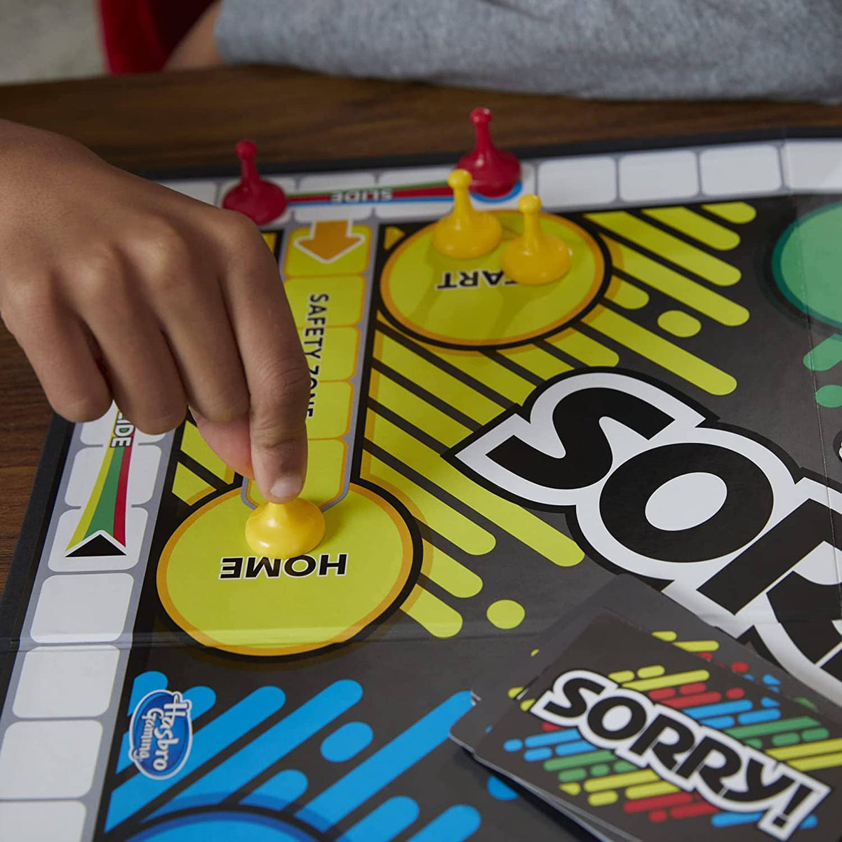 Sorry! board game board with yellow HOME pawn and a hand placing a piece